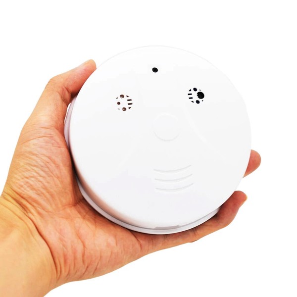 Hand holding a white smoke detector.