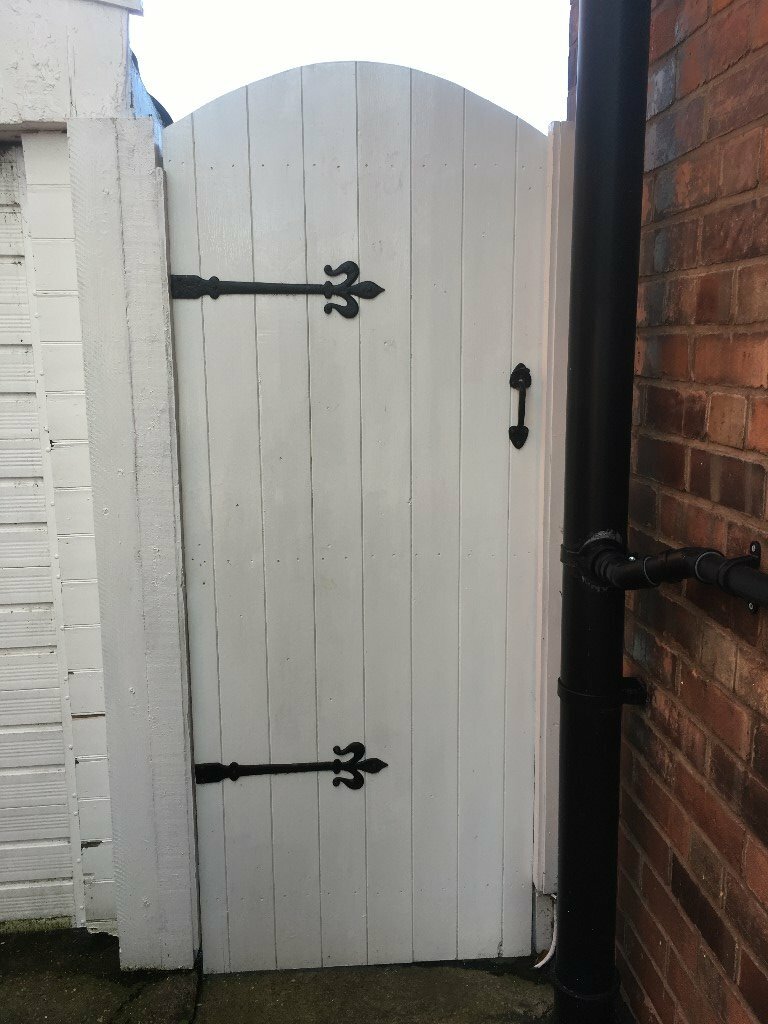 White pained wooden arched gate, about 7ft tall with black furniture