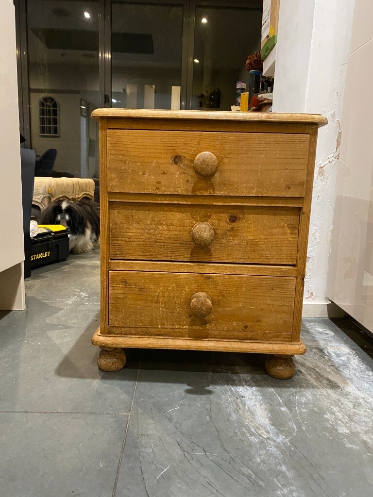 Cute goldencoloured pine bedside with three drawers and bun