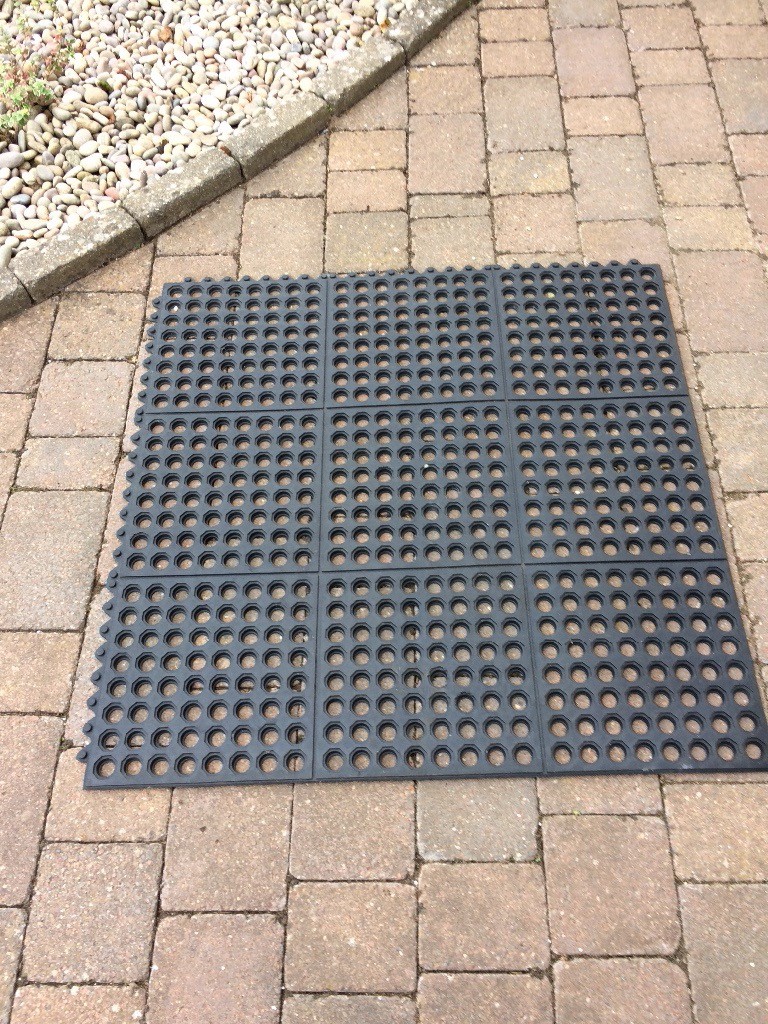 Black rubber interlocking square matting with drainage holes in