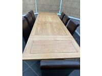 Large wooden extendable dining table with eight chairs.