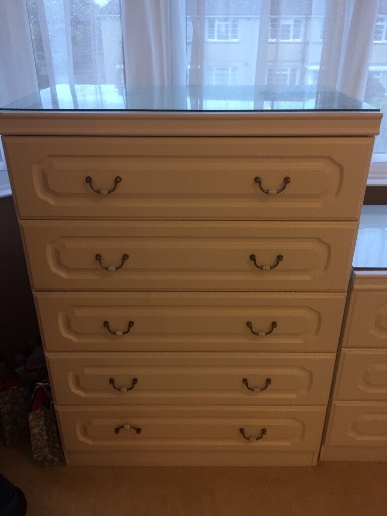 Two white chest of drawers and a matching dressing table/desk. in