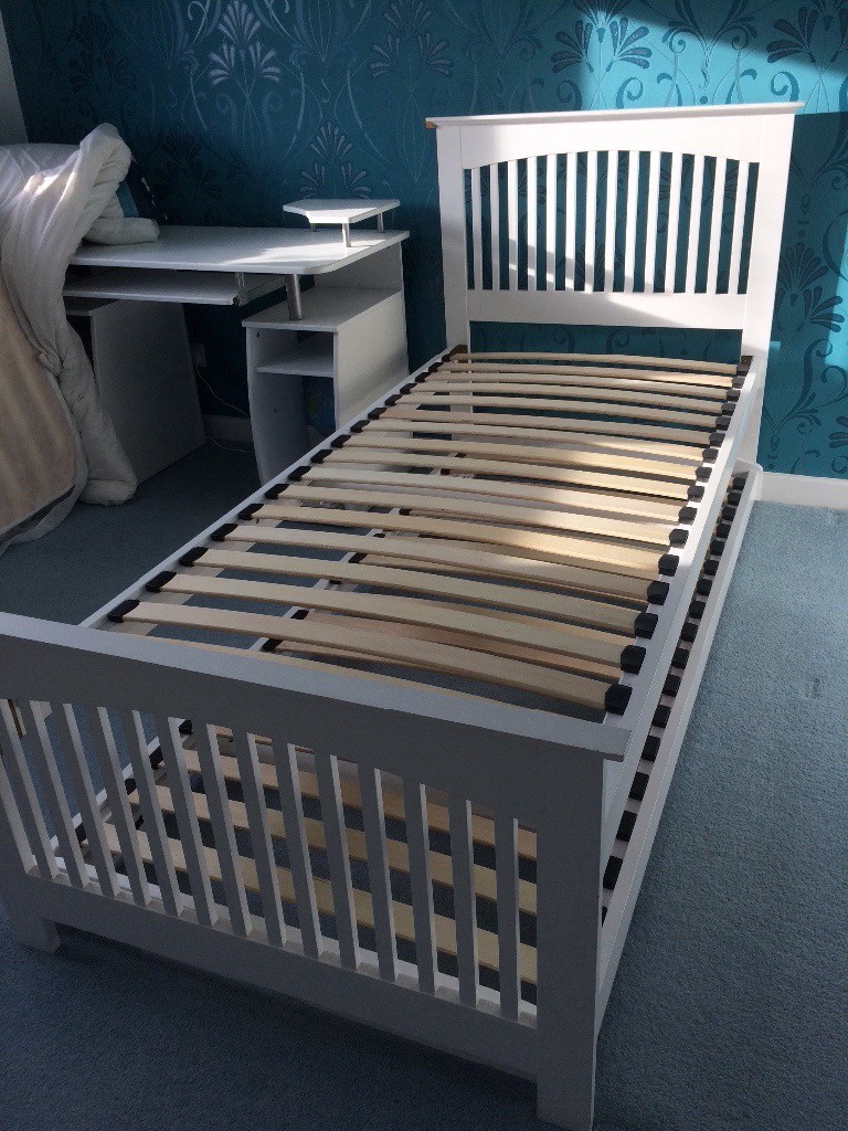 White single bed frame with head board, trundle bed stored underneath