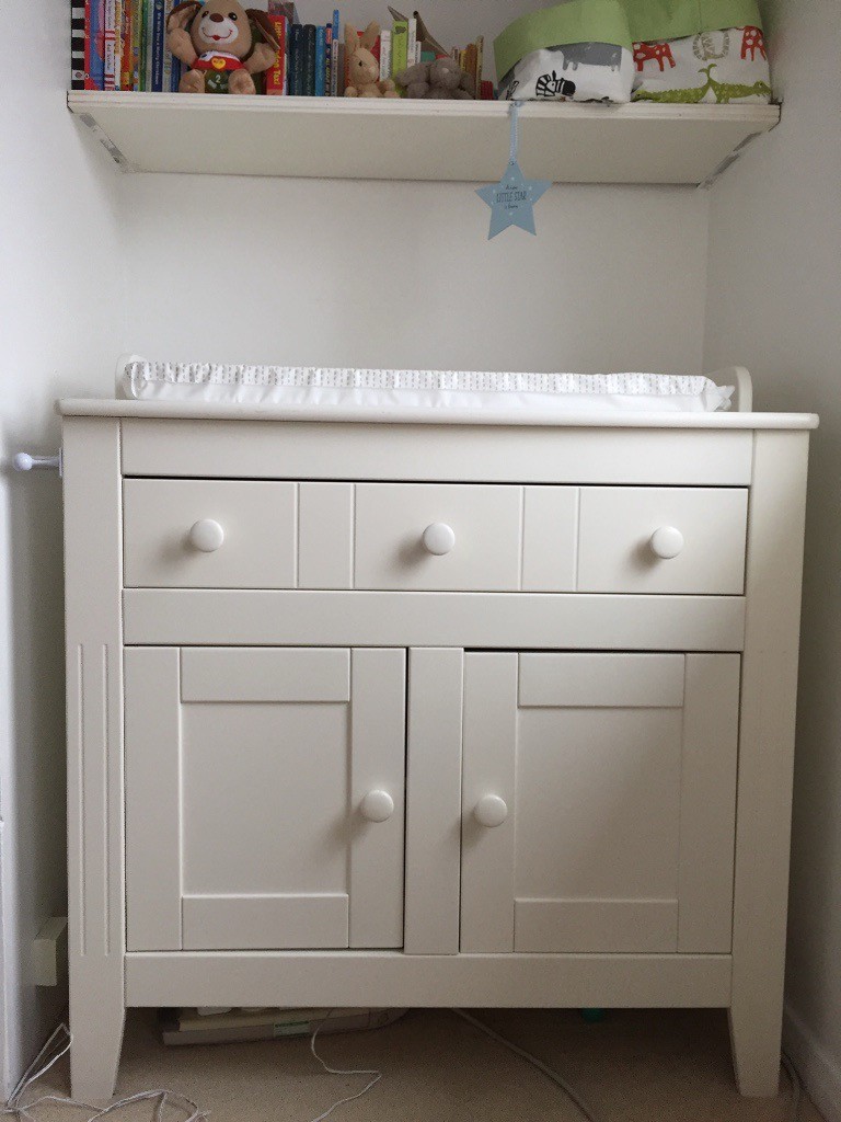 White baby changing table with double cupboard storage and towel rail