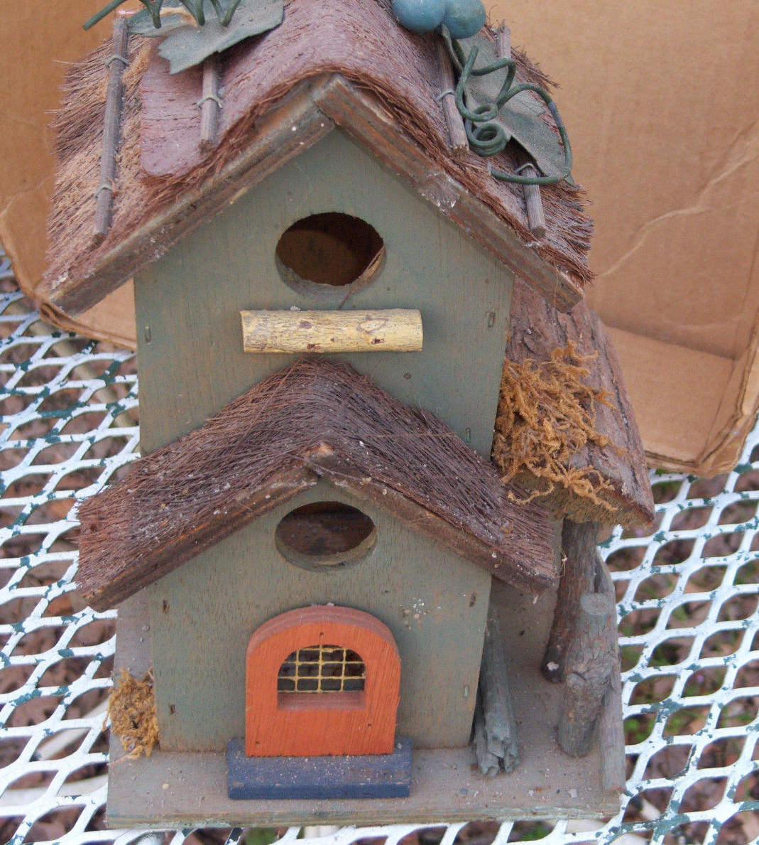 Wooden condo birdhouse decorated with metal leaves and a metal hanger