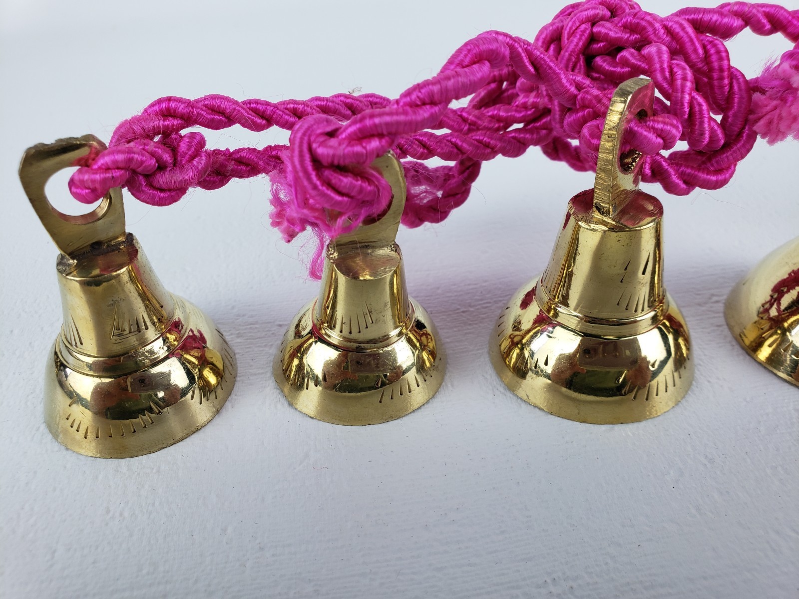 4 Brassy Bells Strung on a Pink Rope India Same Shape Different Sizes