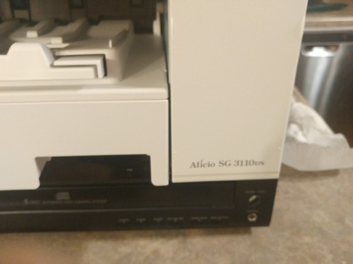 ricoh sg 3110dn printer with extra cartridges and paper.