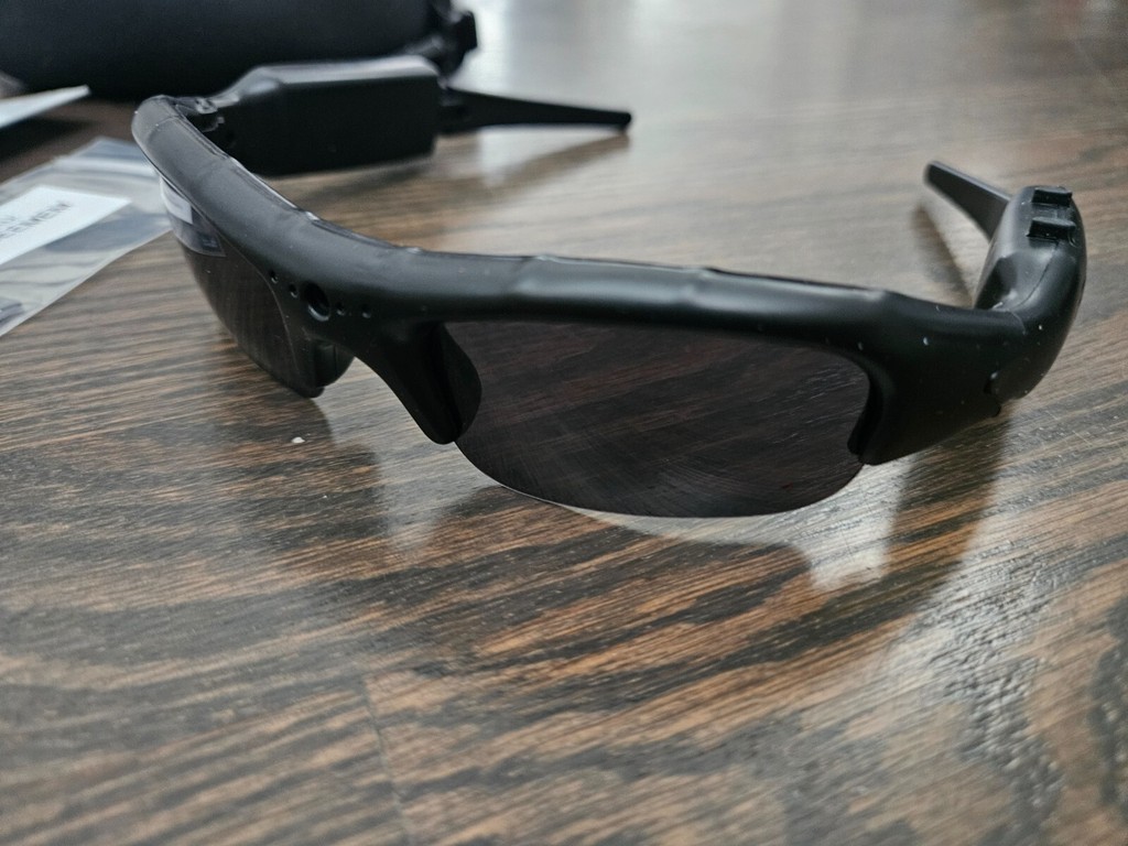 Black smart sunglasses on wooden surface.