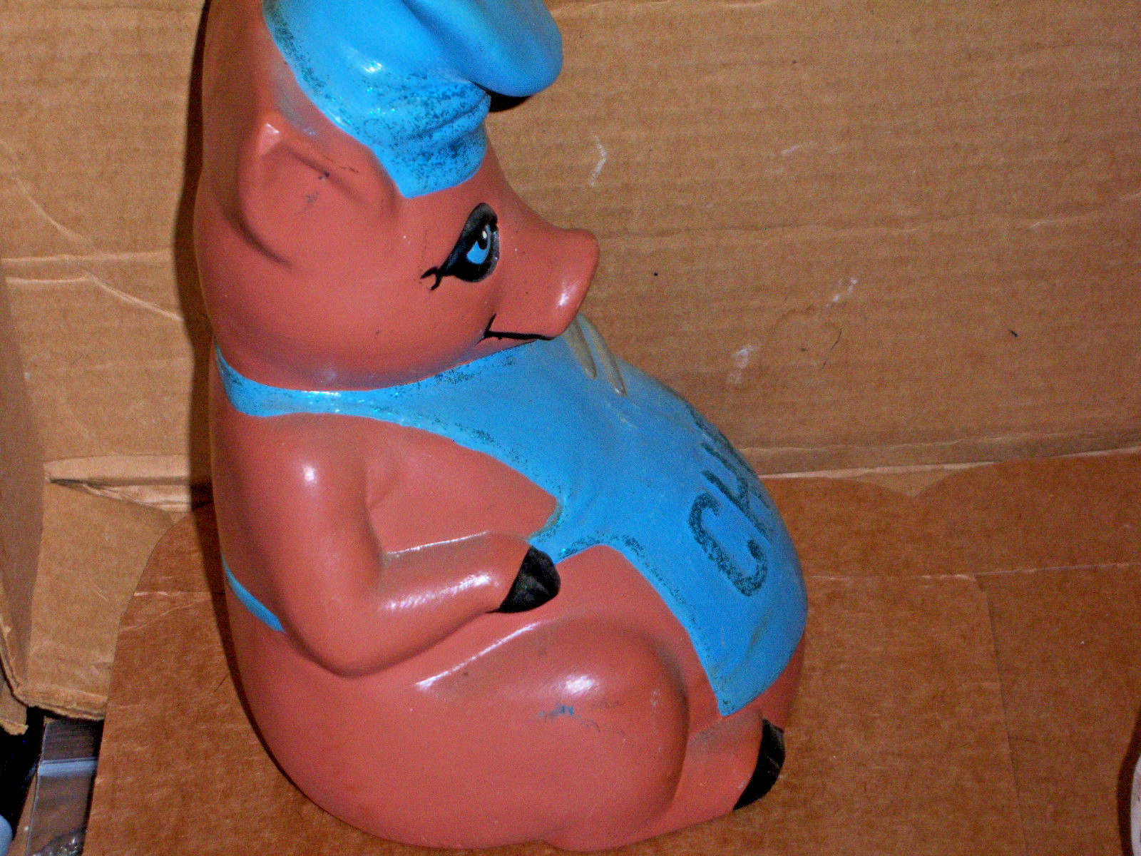 Pig holding a silver fork and wearing a blue apron marked CHEF