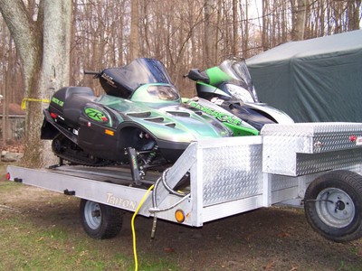 Two Artic Cat snowmobles Trailer and riding apparel