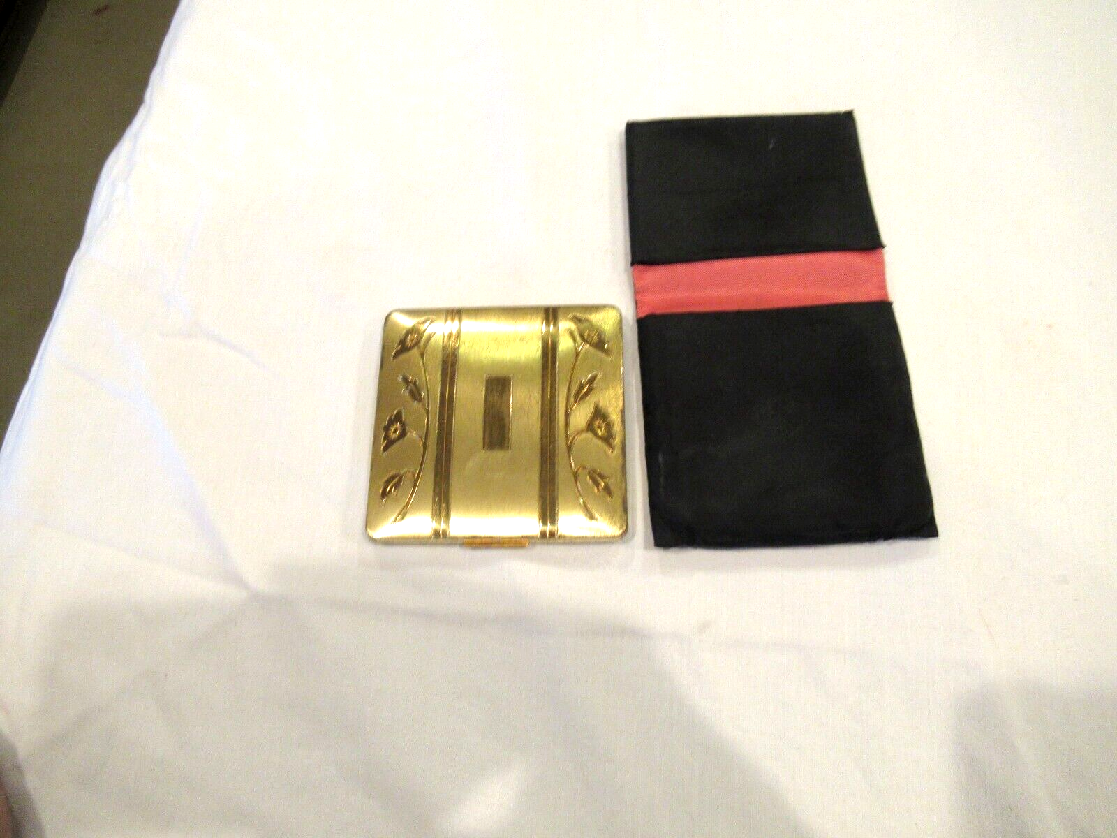 Vintage gold-colored metal compact, lilies, in black fabric case