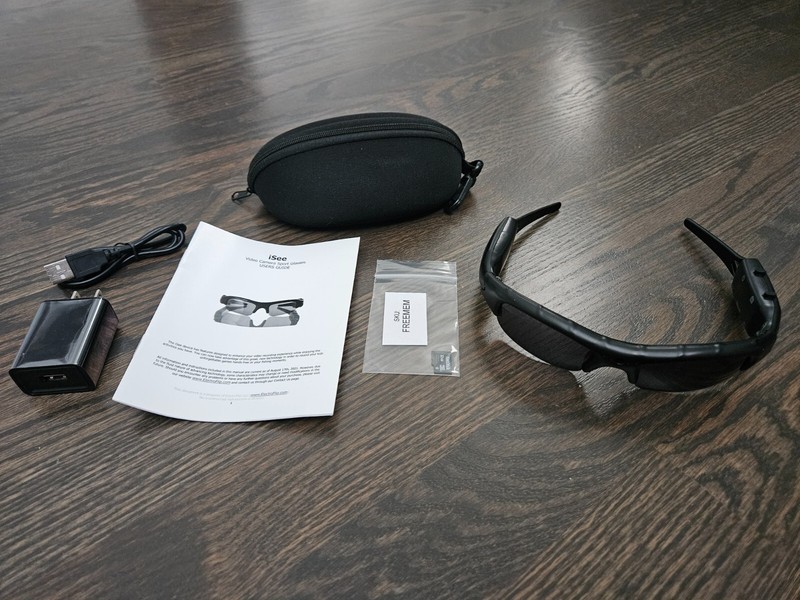 Smart glasses with accessories on wooden floor.