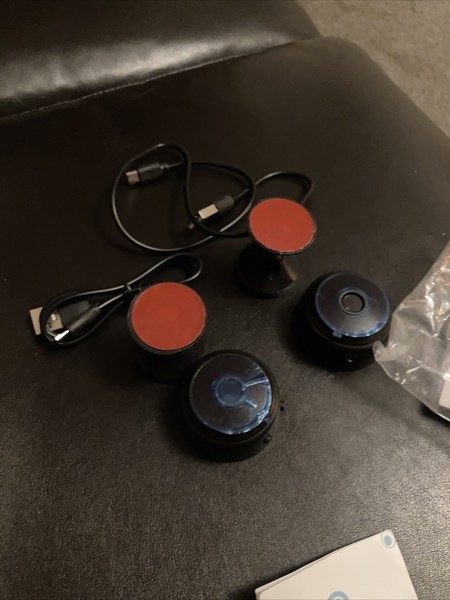 Black wireless earbuds with charging cables on dark surface.