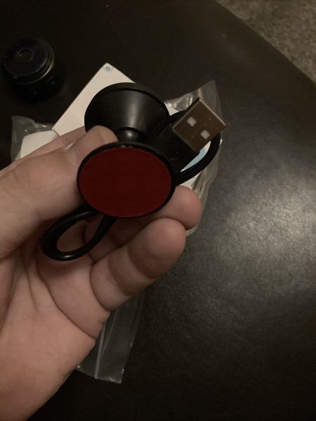 Hand holding a circular red USB device