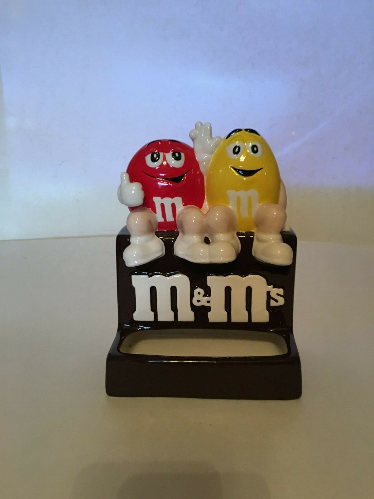 M&M Ceramic Candy Dispenser Red & Yellow Sitting atop Chocolate M&M
