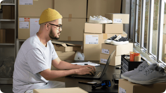 A man in a yellow beanie typing on a laptop linking to eBay Academy page
