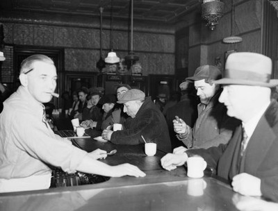 Group men coats caps eat drink as they sit bar an establishment fr- 1943 Photo