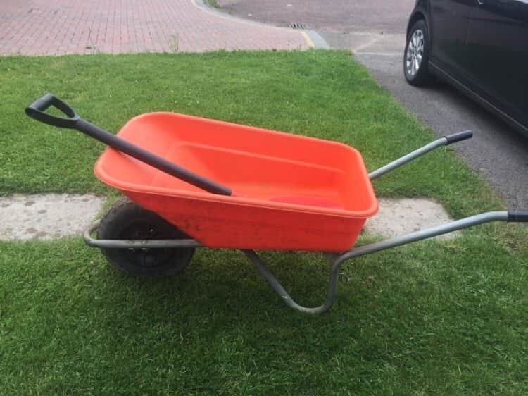 orange and black wheelbarrow and matching spade in Prestbury