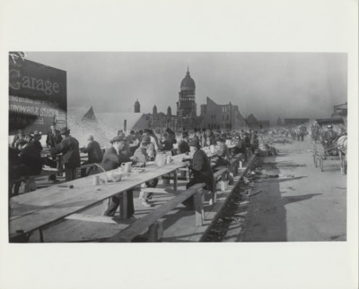 PHOTO OF COMMUNAL LUNCH W/ BOMBED BUILDING FROM NEGATIVE ON PHOTO PAPER