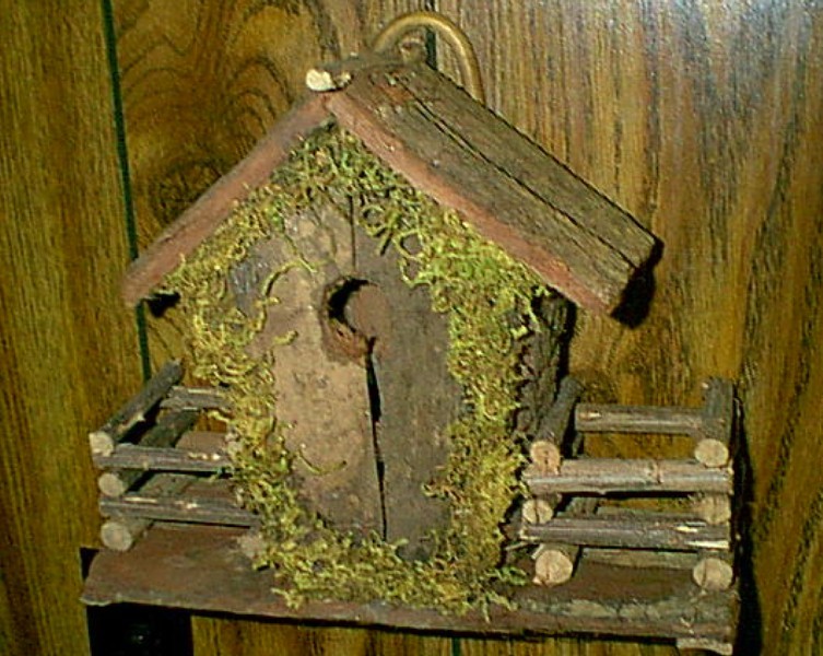 Wooden bird  house decorated with straw and a carral on each side