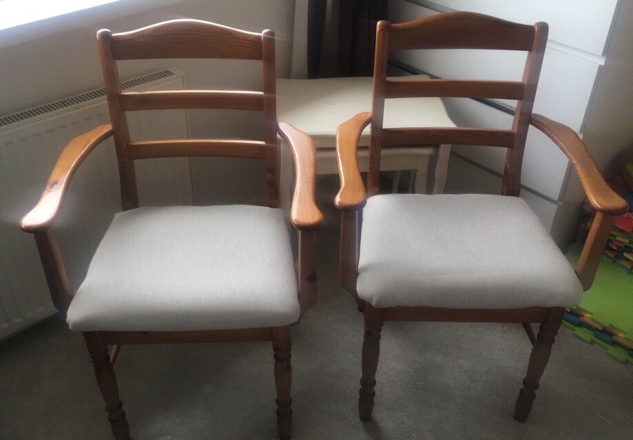 2 wooden matching dining room chairs with high backs and arm rests in