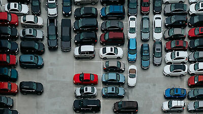Draufsicht auf einen Parkplatz, auf dem PKWs in verschiedenen Farben stehen
