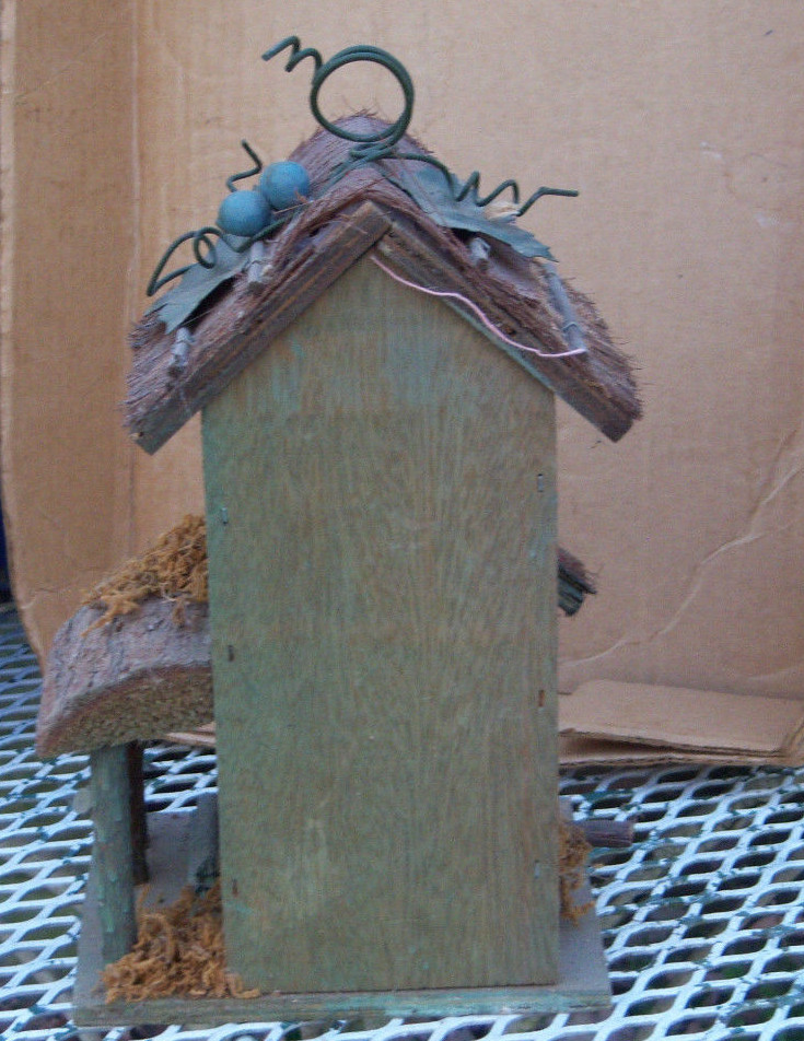 Wooden condo birdhouse decorated with metal leaves and a metal hanger