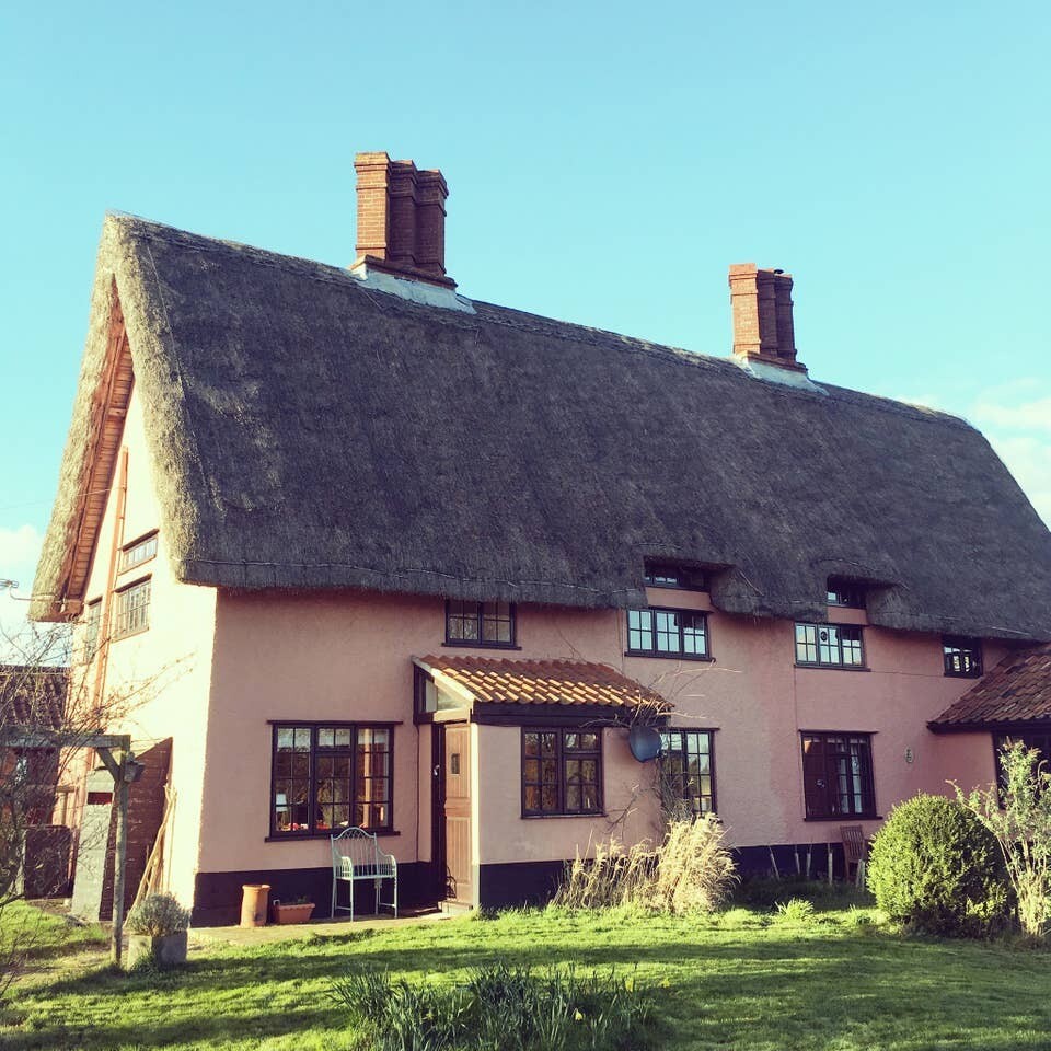 Classic pink Suffolk thatch cottage, picturesque countryside field