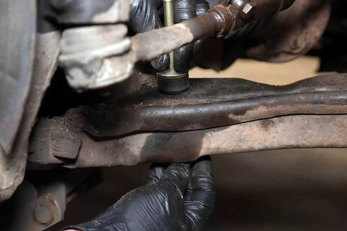 A mechanic slides the inner bushing and washer onto the end link bolt.