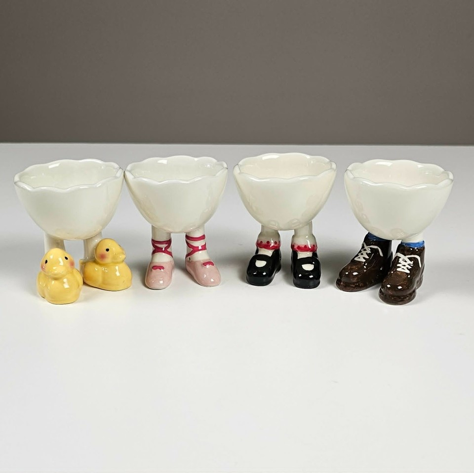 A set of four egg cups with little walking legs — anthropomorphic breakfast surrealism at its finest.