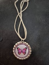 A butterfly bottle cap on a shorter string