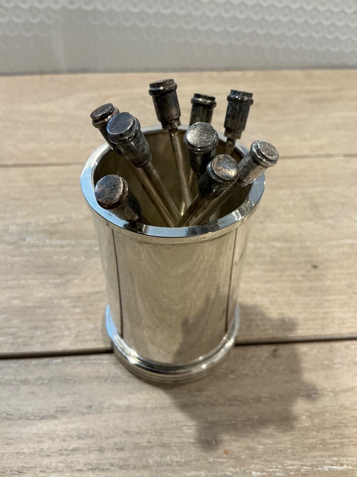 Silverplated cocktail picks with a proper holder — the kind of forgotten barware detail that makes a home bar feel genuinely distinguished.