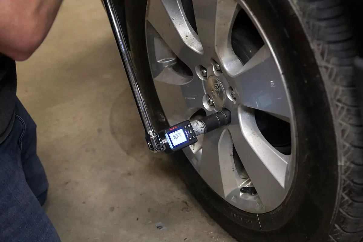 A mechanic using a torque wrench on a lug nut.
