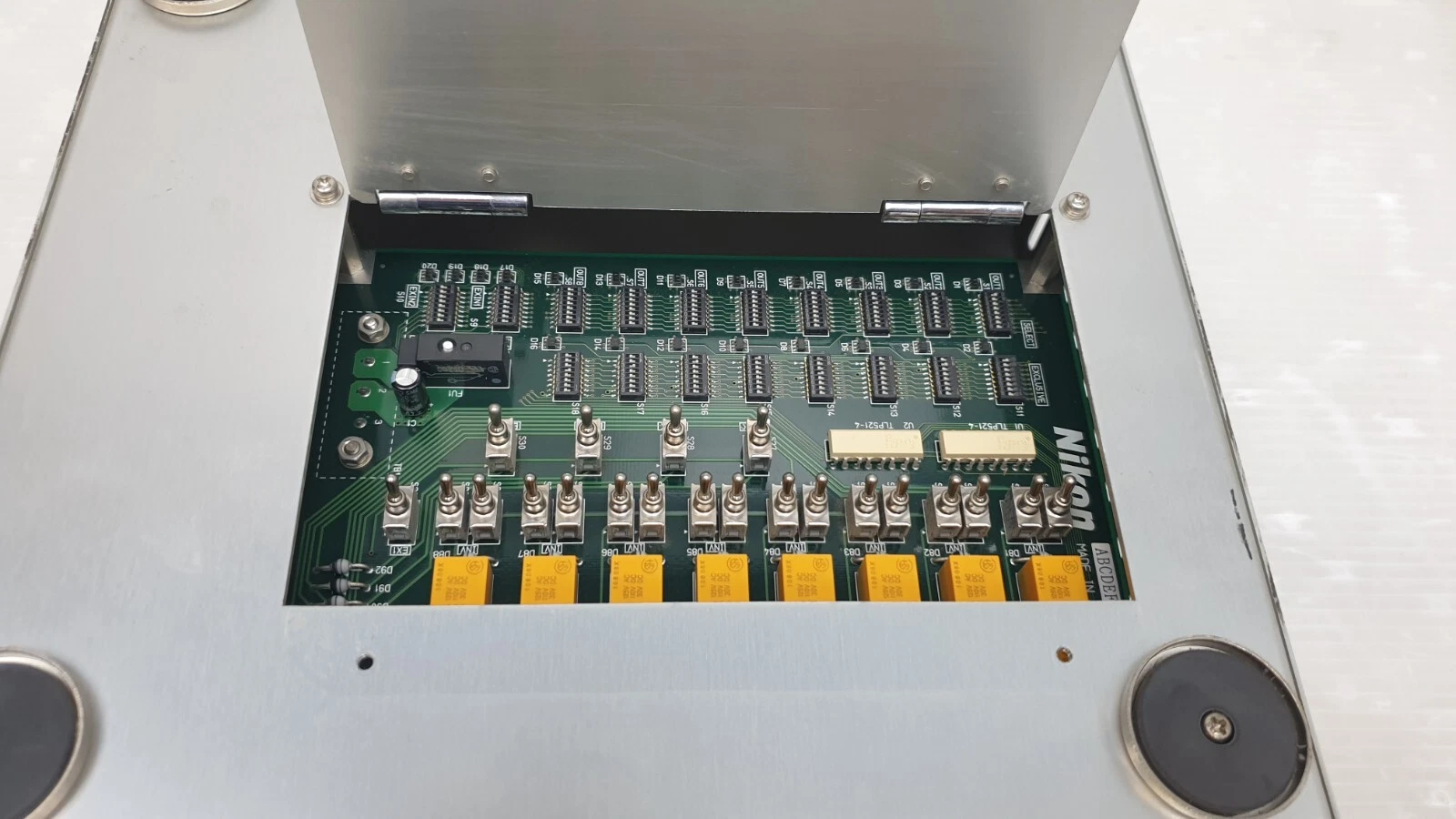Hinged cover open, Nikon PCB with rows of DIP switches and toggle switches