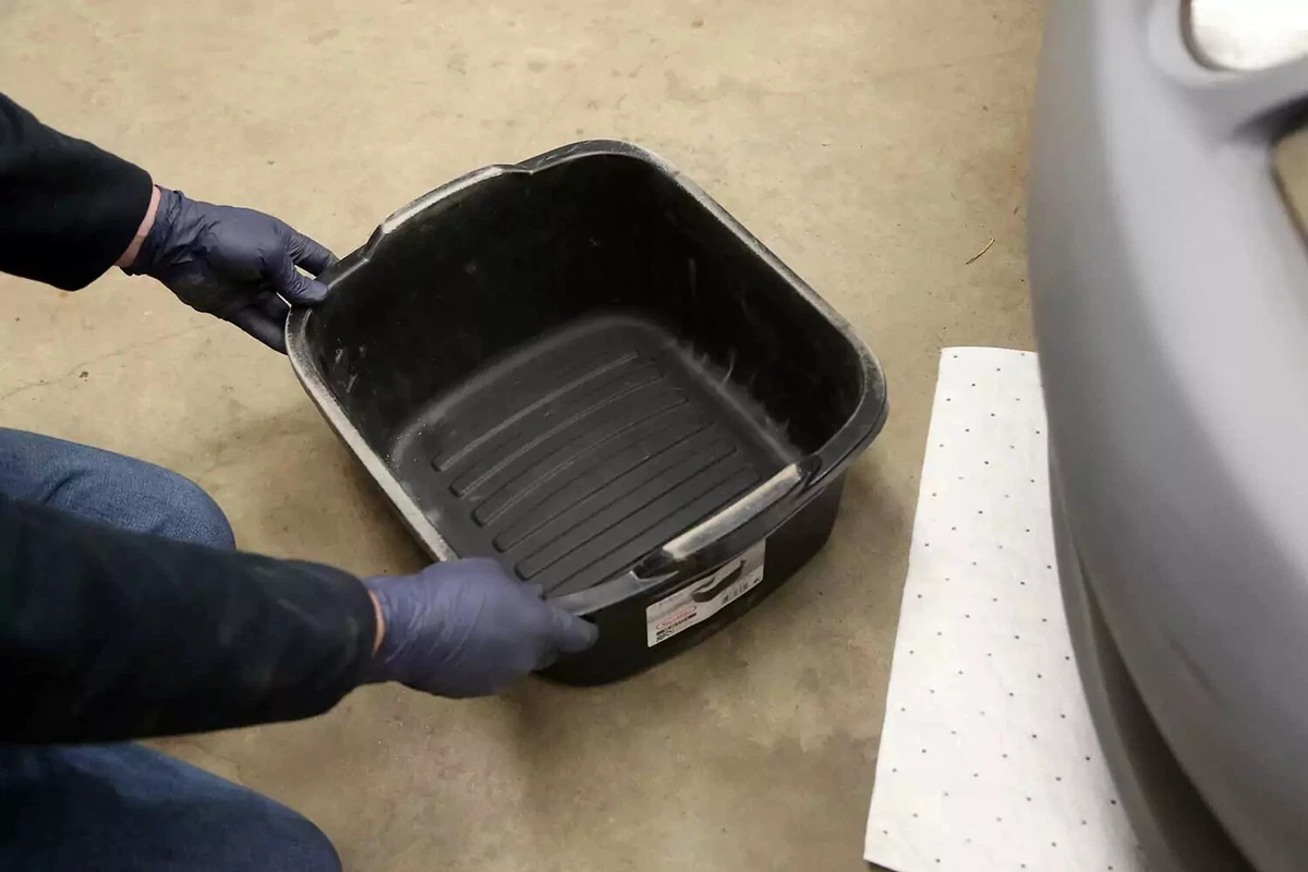Sliding a large drain pan under the radiator’s drain port.