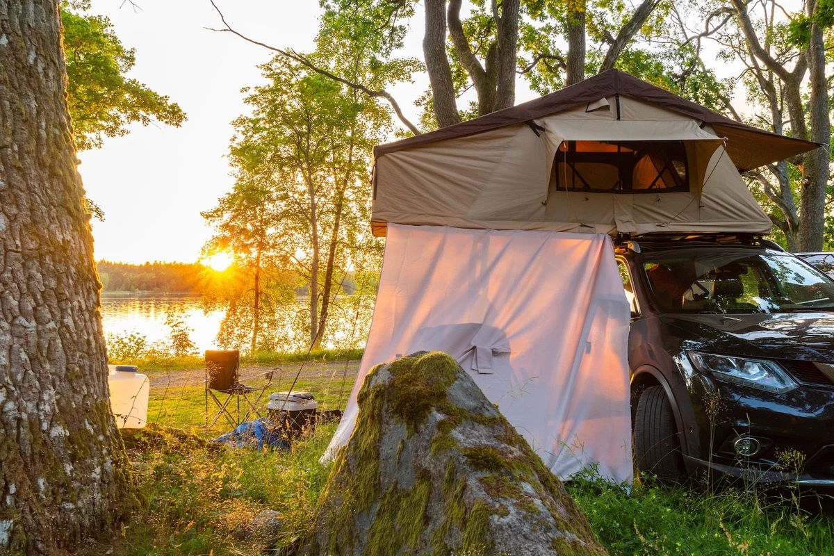 Suv with a roof top tent at sunset by a lake
