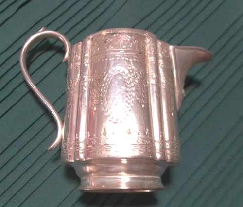Interesting old milk jug in silver or silver-plated. Hand hammered decor.