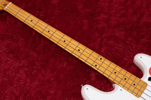 Squier by Fender Classic Vibe 50s Precision Bass in white blonde with gold hardware and four straight string slots on red surface.