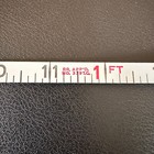 Vintage Stanley 50 foot hand crank tape measure with white face, red vertical scale marked 1 to 50 feet, made in USA.