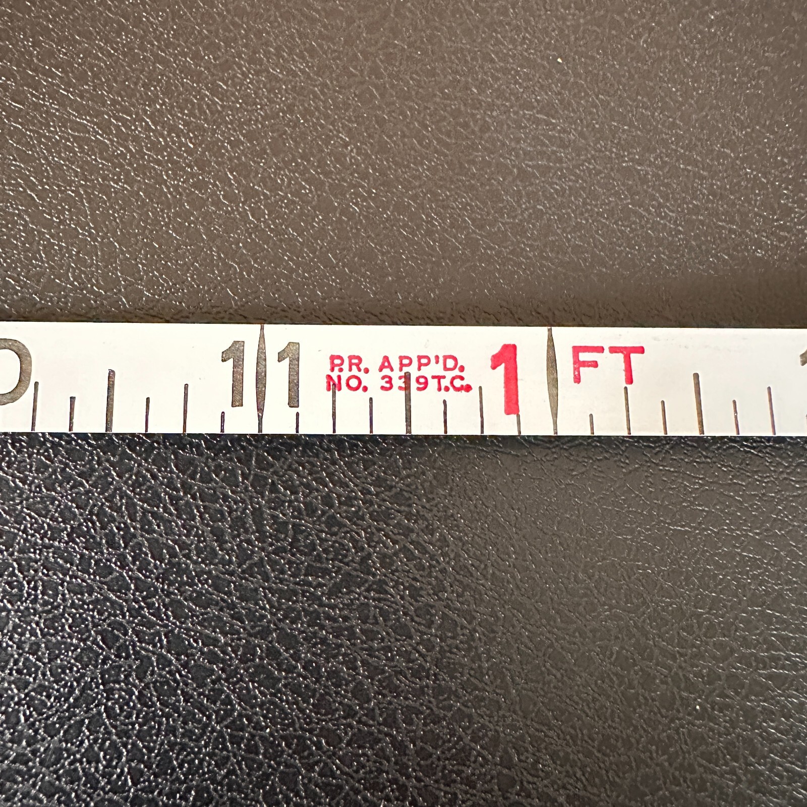 Vintage Stanley 50 foot hand crank tape measure with white face, red vertical scale marked 1 to 50 feet, made in USA.