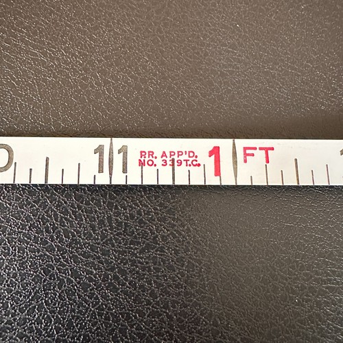 Vintage Stanley 50 foot hand crank tape measure with white face, red vertical scale marked 1 to 50 feet, made in USA.