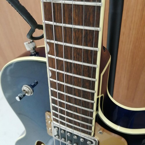 GRETSCH G5655T-QM hollow body electric guitar with silver hardware and dark wood fretboard, positioned against a wooden background.