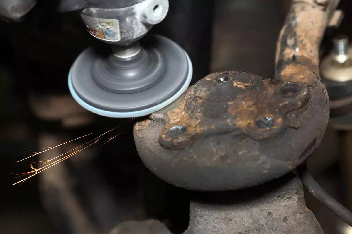 A mechanic uses a grinder to clean up the rivet stalk.