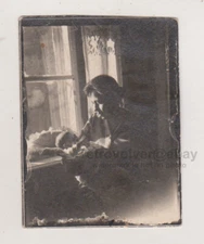 Mother Holding Her Baby Tenderly by the Window Silhouetted Against the Light