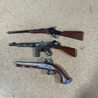 Three metal firearms, tommy gun, flintlock, carbine rifle