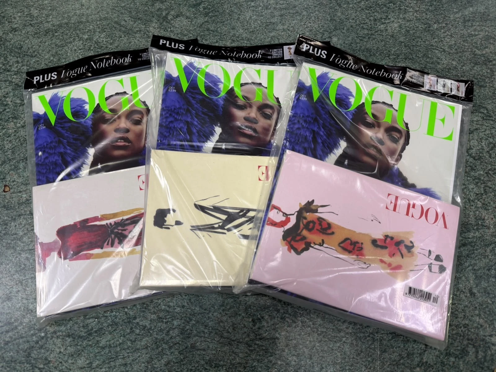 UK Vogue Magazine covers with Wunmi Mosaku in pink/cream dress, Oct 2026 issue, plus two folded notebooks.