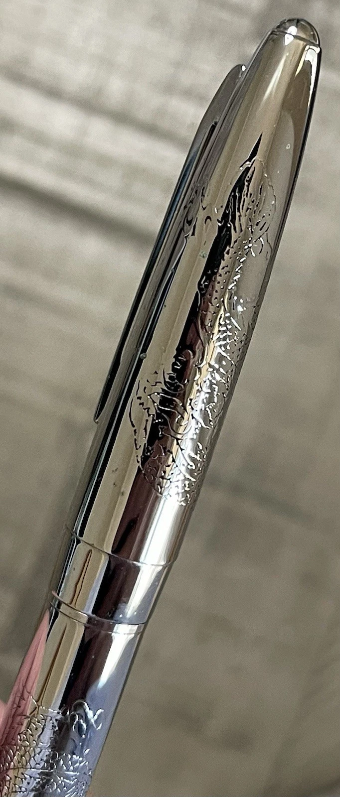Chrome-plated Pilot Namiki fountain pen with fine nib, engraved with intricate dragon and cloud design on body.