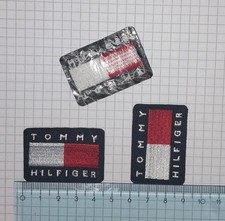 Nr. 3 Toppe Patch Tommy Hilfiger termoadesive, lo sfondo è blu scuro.