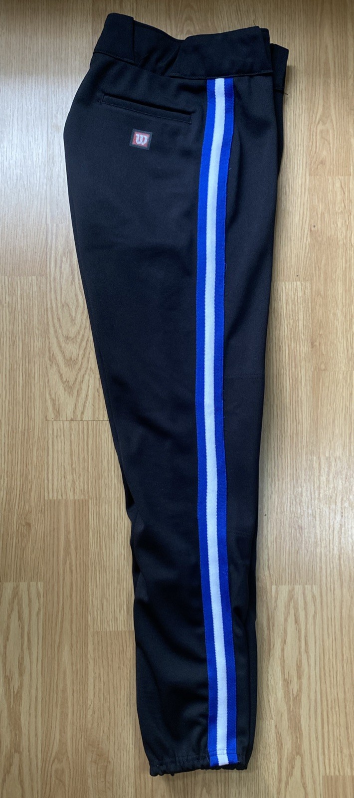 Black Wilson RMB A4409 men’s baseball pants with blue and white vertical stripes on the side, made in the USA.