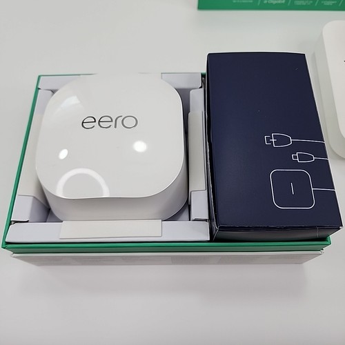 White Eero 6+Plus dual band mesh WiFi router box with black top and side, next to black power adapter box.
